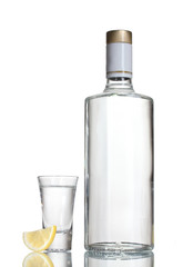 Bottle of vodka and wineglass with lemon isolated on white
