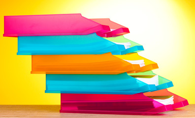 bright paper trays on wooden table on yellow background