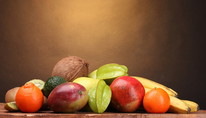 Assortment of exotic fruits on wooden table on brown background