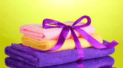 Colorful towels with ribbon on green background