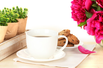 cup of coffee, cookies and flowers on table in cafe