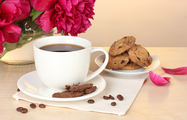 cup of coffee, cookies, chocolate and flowers on table in cafe