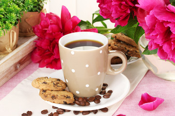 cup of coffee, cookies and flowers on table in cafe