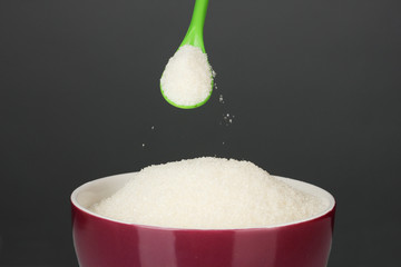 A colorful bowl full of white sugar with bright spoon