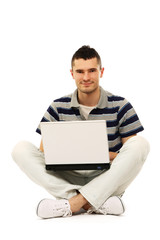 A smiling man working with a laptop on the floor, over white
