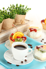 cup of coffee and sweet cakes with fruits on wooden table