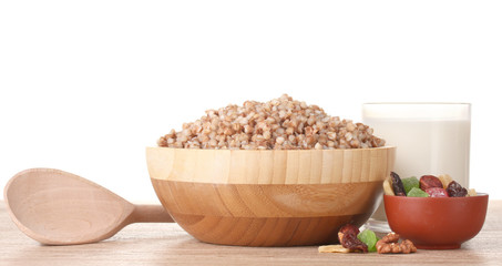 Boiled buckwheat in a wooden bowl with a glass of milk