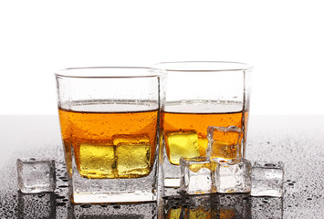 two glasses of scotch whiskey and ice on table isolated on