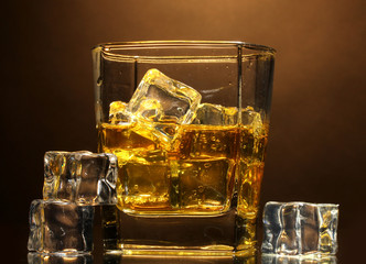 glass of scotch whiskey and ice on brown background
