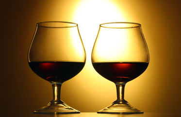 Two glasses of cognac on yellow background
