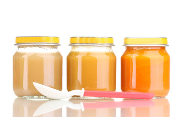 Jars of baby puree and spoon isolated on white