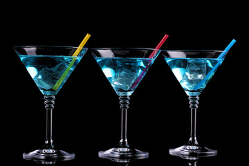 Blue cocktail in martini glasses isolated on black