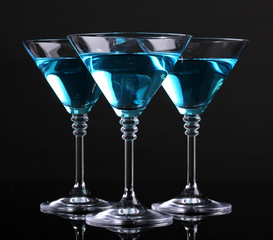 Blue cocktail in martini glasses isolated on black