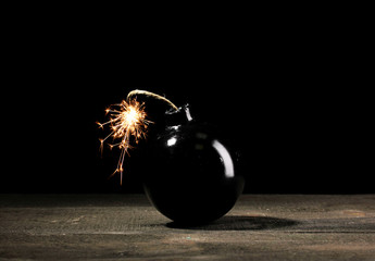 Cartoon style bomb on wooden table on black background