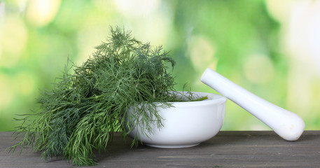 Dill in a mortar and pestle on green background