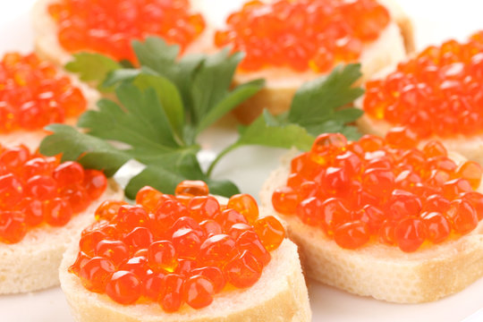 Red caviar on bread on white plate close-up