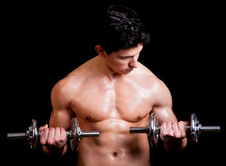 Fototapeta na wymiar Young muscular man lifting weights on black background
