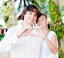 Attractive couple in white showing heart with their hands