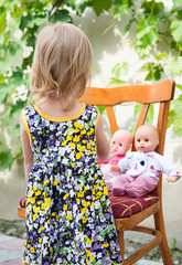 Fototapeta premium A little girl plays with dolls