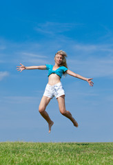 The happy young woman jumps in the field