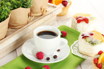 cup of coffee and sweet cakes with fruits on wooden table