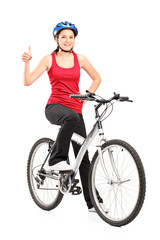 Female bicyclist posing on a bicycle and giving a thumb up