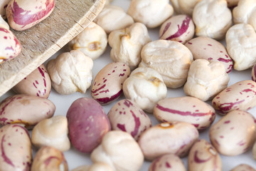 Beans and chickpeas on wooden spoon and a white background