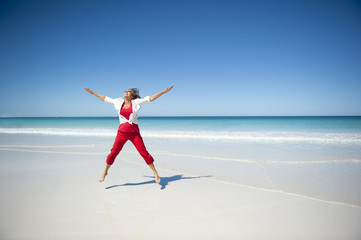 Joyful mature woman jumping tropical beach