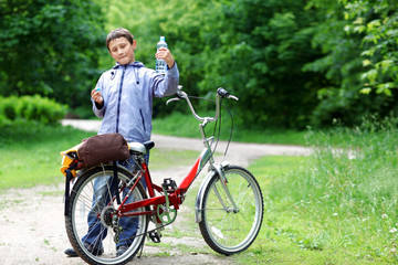 Fototapeta premium Young boy with bicycle with clear water relaxing outdoors