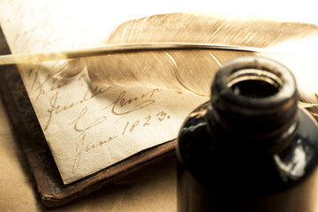 Old book with feather and inkpot