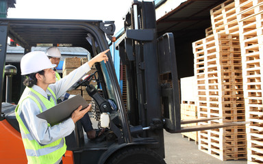 warehouse workers team at unloading works with forklift loader