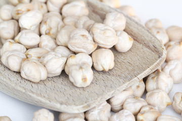 chickpeas on wooden spoon and white background