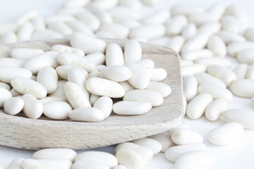 Fototapeta na wymiar White beans on wooden spoon and a white background
