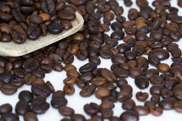 Coffee beans on wooden spoon and a white background