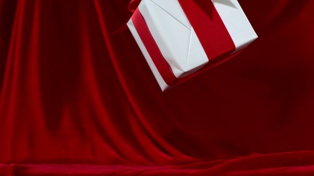 Gift box falling against red fa