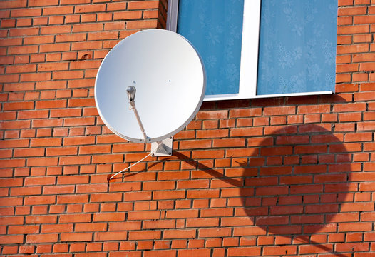 Satellite Dish mounted on  brick wall.