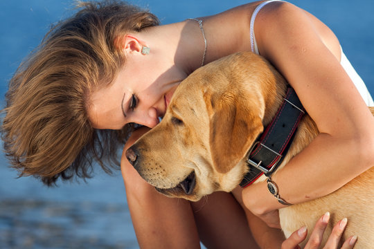 Young woman with Labrador male dog on background of the sea