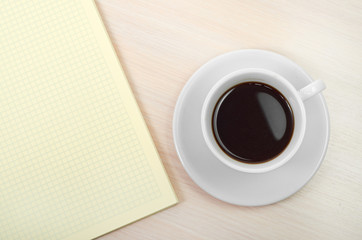 Coffee cup with note book on table