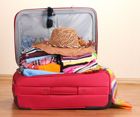 Open red suitcase with clothing in the room