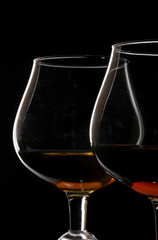 Two glasses of cognac on black background