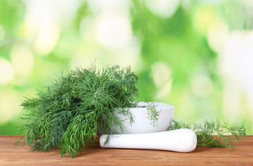 Dill in a mortar and pestle on green background