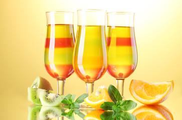 fruit jelly in glasses and fruits on yellow background