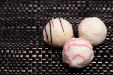 Drei weiß Pralinen auf dunklem Stoff