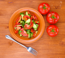 Fresh salad with tomatoes and cucumbers on wooden background