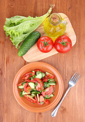 Fresh salad with tomatoes and cucumbers on wooden background