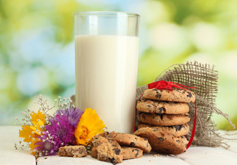 glass of milk, chocolate chips cookies with red ribbon and
