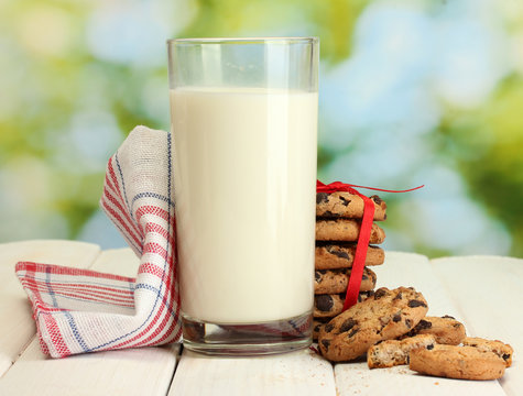 glass of milk, chocolate chips cookies with red ribbon and