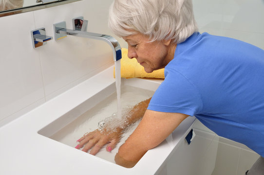Seniorin macht Wechselbäder im Waschbecken
