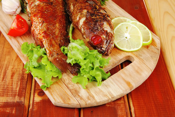 main portion of two grilled fish served on wood