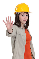 A female construction worker doing a stop sign.